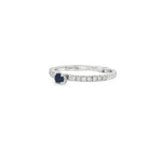 Angled view of white gold diamond band ring showing raised blue centre sapphire