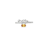 White gold ring with oval orange sapphire below an angled baguette diamond crown